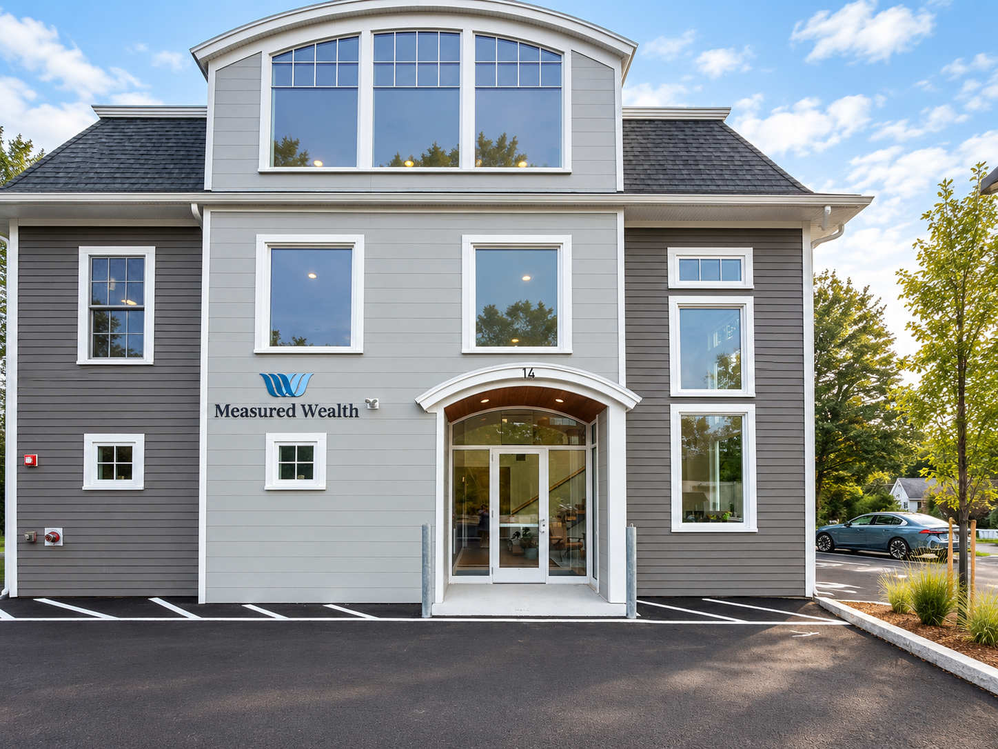 Front of the Measured Wealth office, a gray building with the Measured Wealth sign beside the arched entrance marked 14.