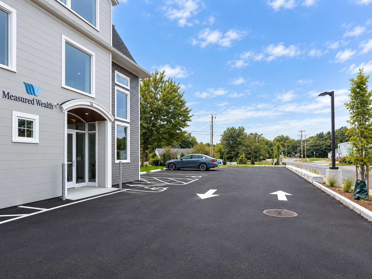 Measured Wealth parking area with painted direction arrows and accessible spaces beside the building.